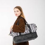 femeie calatorind cu o geanta cu imprimeu zebra pe umar